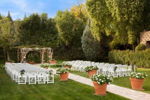 斯科茨斯科茨代尔希尔顿逸林度假酒店的户外婚礼仪式,配有白色椅子和拱门