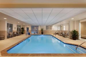 亚特兰大Embassy Suites by Hilton Atlanta Airport的酒店大堂的大型游泳池,配有椅子