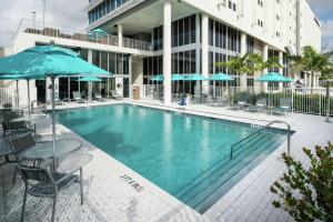 迈阿密DoubleTree by Hilton Miami Doral的大楼前的游泳池配有椅子和遮阳伞
