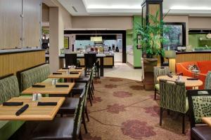 阿尔法利塔亚特兰大北/阿尔法利塔希尔顿花园酒店的一间带木桌椅的餐厅和一间酒吧