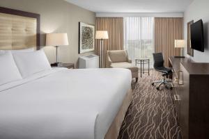 堪萨斯城希尔顿堪萨斯城机场酒店的酒店客房,配有一张床、一张桌子和椅子