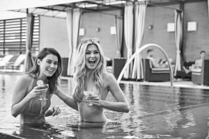 达拉斯达拉斯高地希尔顿古玩收藏酒店的两个妇女在游泳池内,持有酒杯