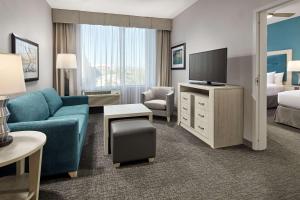 长滩长滩机场希尔顿惠庭套房酒店 的客厅配有蓝色的沙发和电视