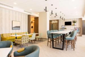 迈阿密Hampton Inn & Suites Miami Wynwood Design District, FL的一间带桌椅和电视的用餐室