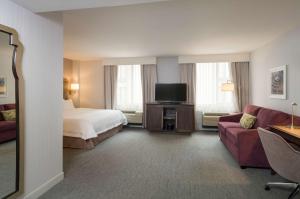 纽约曼哈顿时代广场南希尔顿恒庭酒店的酒店客房配有床、沙发和电视。