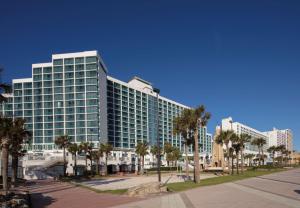 代托纳海滩代托纳比奇希尔顿酒店 的一座高大的建筑,前面有棕榈树