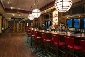 代托纳海滩代托纳比奇希尔顿酒店 的餐厅内的酒吧,配有红色的椅子和灯