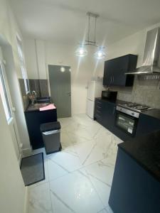 莱斯特Luxury Fully Furnished Bedroom的厨房配有黑色橱柜和白色瓷砖地板。