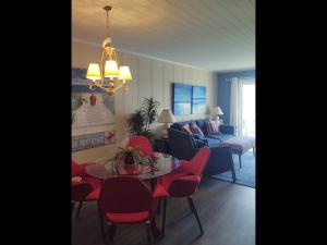 霍尔顿海滩Next 2 Paradise-203的客厅配有桌子和红色椅子