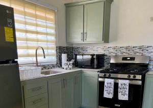 ArimaPeaceful Fully Equipped 3BR Villa的厨房配有绿色橱柜、炉灶和水槽。