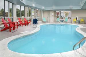 朗蒙特Home2 Suites By Hilton Longmont的一个带红色和蓝色椅子和桌子的大型游泳池