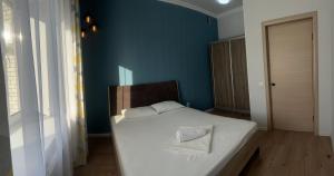 乌拉尔斯克Уютная и комфортная 3х комнатная квартира со всеми условиями的卧室配有白色床和蓝色墙壁