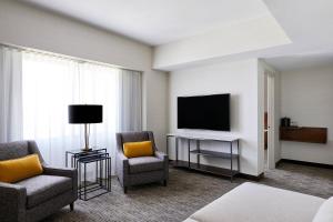 梅萨Delta Hotels by Marriott Phoenix Mesa的酒店客房设有电视、两把椅子和一张桌子