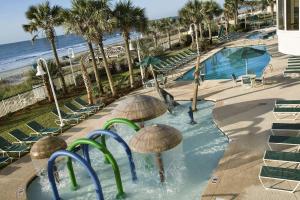 默特尔比奇默特尔比奇海滨汉普顿酒店套房的海滩旁的游泳池配有遮阳伞和椅子