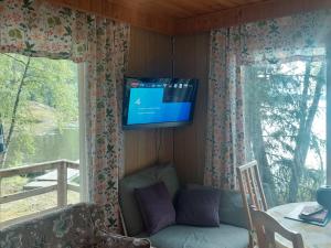 Lakeside Hilda, rantamökki的客厅配有沙发和墙上的电视