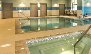 林伍德西雅图/林恩伍德希尔顿惠庭套房酒店的酒店大堂的游泳池,配有椅子和桌子