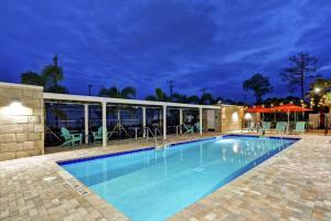 代托纳海滩Home2 Suites By Hilton Daytona Beach Speedway的一个带桌椅的夜间游泳池