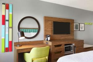 好莱坞劳德代尔堡机场汉普顿酒店及套房的一间卧室配有电视、椅子和镜子