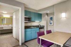 好莱坞劳德代尔堡机场汉普顿酒店及套房的厨房配有蓝色橱柜和一张带紫色椅子的桌子
