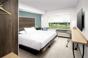 路易斯威尔Tru By Hilton Louisville East Ky的一间卧室配有一张床、一张书桌和一个窗户。