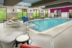 路易斯威尔易斯维尔东斯特波希尔顿欣庭套房酒店的游泳池位于酒店客房内,配有椅子和桌子