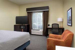 ClintonHampton Inn Knoxville Clinton I-75的酒店客房配有一张床、一把椅子和一台电视。