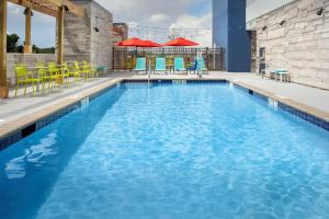 哥伦比亚Home2 Suites By Hilton Columbia Southeast Fort Jackson的游泳池配有蓝色的水和黄色的桌椅