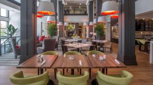 查尔斯顿查尔斯顿水滨/市中心希尔顿花园酒店的餐厅设有木桌和绿色椅子