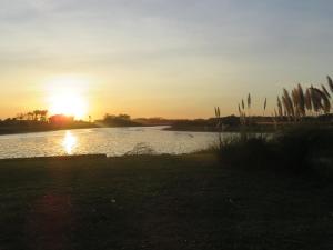 奇基塔湖巴尔内阿里奥COMPLEJO LA ISLA MAR CHIQUITA的日落在水体上,日落在太阳下