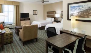 卡纳维拉尔角卡纳维拉尔角-可可比奇希尔顿惠庭套房酒店的酒店客房带两张床和一张桌子以及椅子。