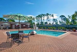 巴拿马城海滩Hampton Inn by Hilton Panama City Beach的一个带桌椅和遮阳伞的游泳池