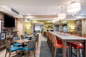 巴尔的摩Hampton Inn Baltimore Bayview Campus的餐厅设有长长的酒吧,配有桌椅