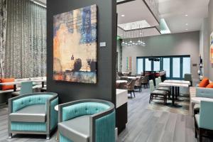 亚特兰大Hampton Inn & Suites Atlanta Buckhead Place的餐厅设有桌椅,墙上挂有绘画作品