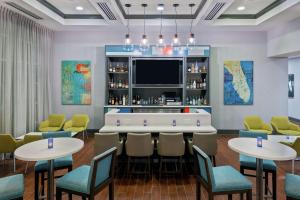 奥兰多汉普顿酒店 - 奥兰多机场村庄通道的餐厅内的酒吧配有桌椅
