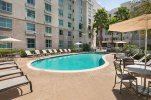 坦帕Homewood Suites by Hilton酒店坦帕机场 - 西岸的一座带桌椅的游泳池以及一座建筑