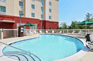 诺克斯维尔Hampton Inn & Suites Knoxville-Turkey Creek Farragut的酒店前的游泳池配有椅子和遮阳伞
