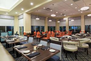 坦帕坦帕机场/韦斯特舒尔希尔顿花园酒店的餐厅设有木桌、椅子和窗户。