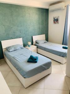 圣保罗湾城Mela Apartment 1的卧室设有两张床铺,配有蓝色床单