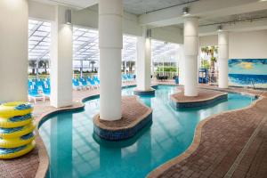 默特尔比奇Homewood Suites by Hilton Myrtle Beach Oceanfront的拥有白色柱子和蓝色水的游泳池