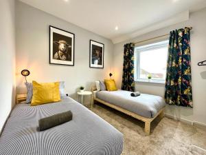 浦耳Brand New 3 Bedroom House -Sleeps 6 - Free Parking - Great Location - Fast WiFi - Smart TV - sleeps 6! Close to Poole & Bournemouth & Sandbanks的一间卧室设有两张床和窗户。