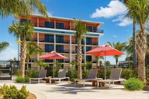 圣徒皮特海滩Hilton Garden Inn St. Pete Beach, FL的棕榈树、椅子和红伞的酒店