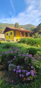 圣本图-杜萨普卡伊Pousada VISTA LINDA的院子里的黄色房子,鲜花盛开