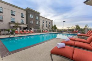 波威圣地亚哥波威希尔顿恒庭旅馆&套房酒店的一座游泳池,旁边设有红色躺椅