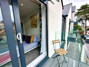 浦耳Stunning Brand New House - Sleeps 6 - Free Parking - Great Location - Fast WiFi - Smart TV - Close to Poole & Bournemouth & Sandbanks的阳台配有椅子和沙发,位于门廊上