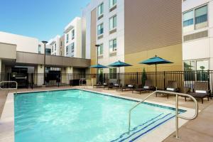 圣何塞Homewood Suites By Hilton San Jose Santa Clara的一座带椅子和遮阳伞的游泳池位于一座建筑旁边