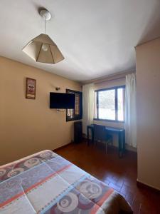 门多萨Open House Hostel的一间卧室配有一张床、一张桌子和一台电视