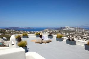 皮尔戈斯Arxegono Cave Houses Santorini的坐在庭院里俯瞰城市的女人
