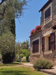 多尔切阿夸La Casa della Luna - Villa con piscina的一座古老的石头建筑,窗户上放着鲜花