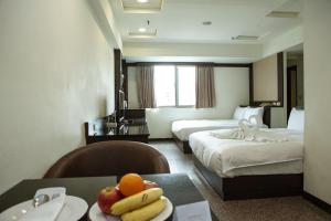 台中市友爱富豪国际大饭店  的酒店客房带两张床和一张桌子,上面有水果