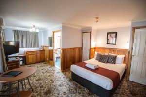 梅林布拉Robyn's Nest Lakeside Resort的酒店客房设有床、桌子和电视。